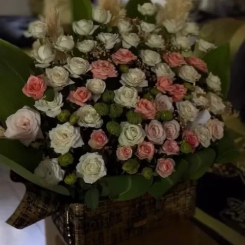 boîte florale avec roses blanches et roses pastel, feuillage vert, présentation élégante