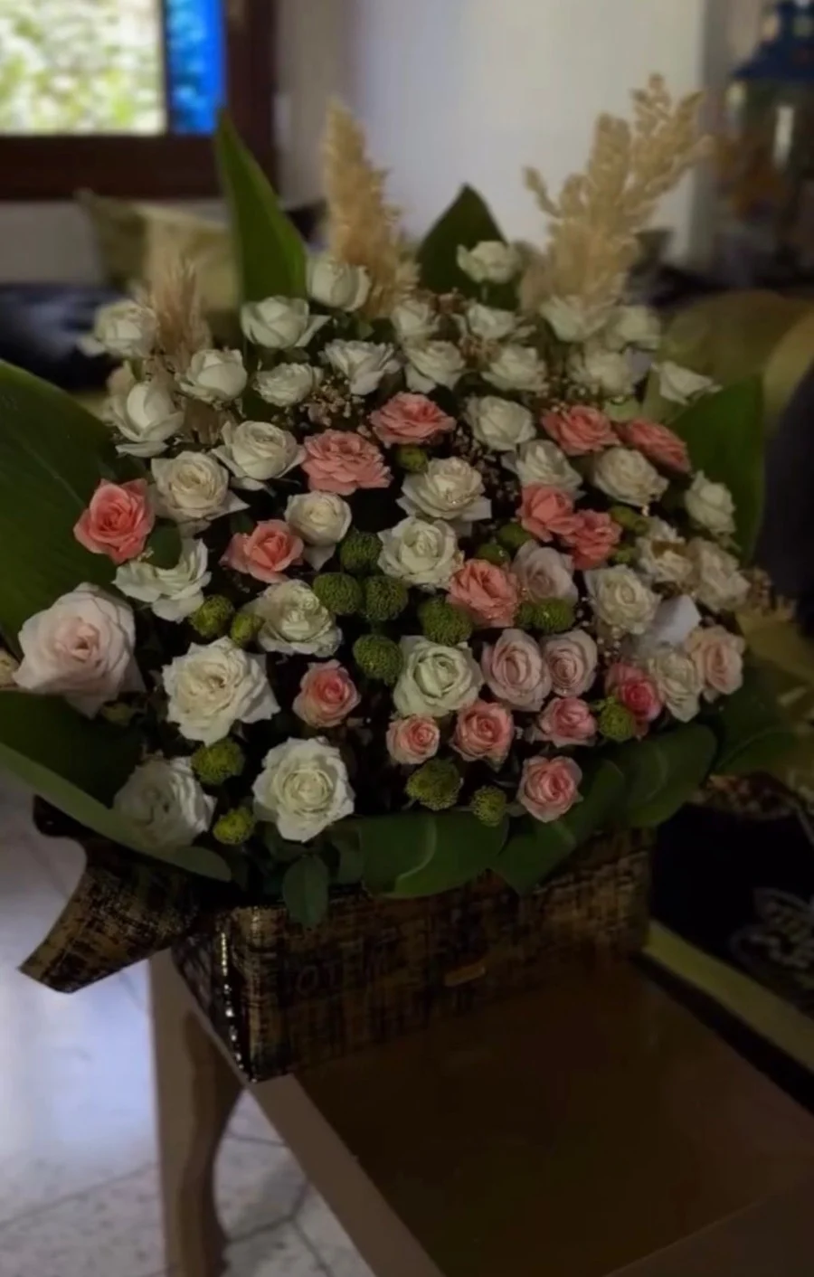 boîte florale avec roses blanches et roses pastel, feuillage vert, présentation élégante