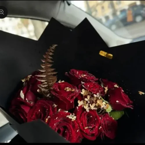 bouquet roses rouges décoré de feuilles dorées dans un papier noir élégant