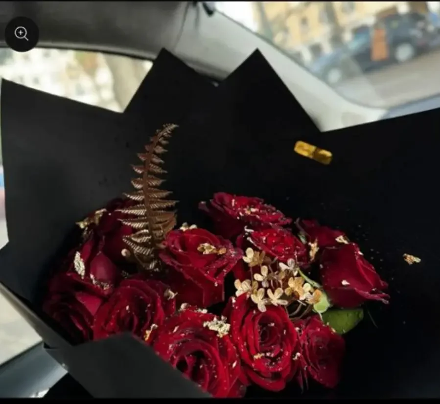 bouquet roses rouges décoré de feuilles dorées dans un papier noir élégant
