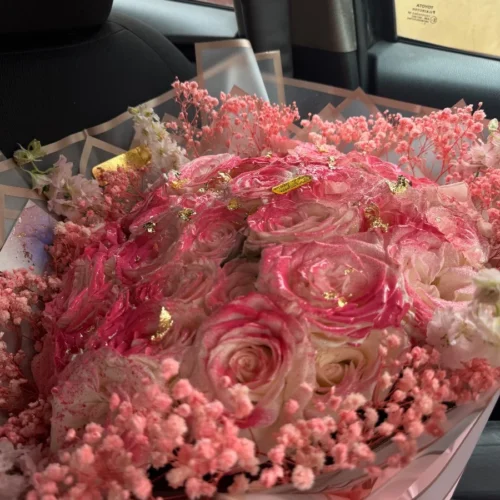 Bouquet de roses roses et blanches avec décor doré et fleurs séchées dans un emballage élégant
