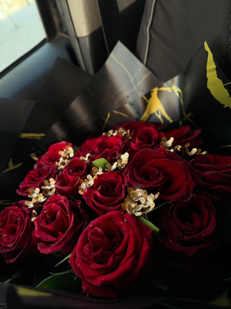Bouquet de roses rouges avec décorations dorées dans un emballage noir élégant