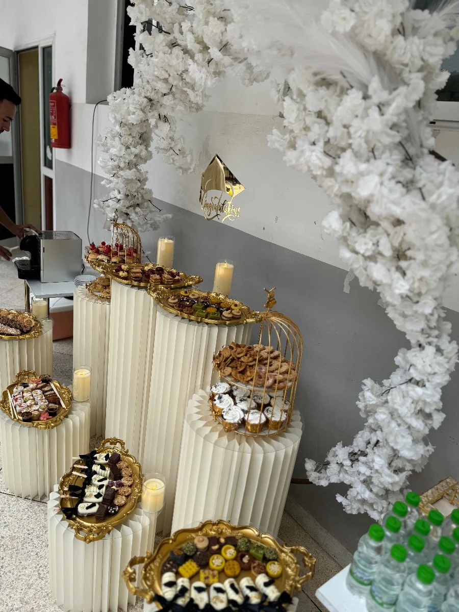 Buffet de luxe à Fès avec présentoirs blancs, plateaux dorés, douceurs et arche florale blanche